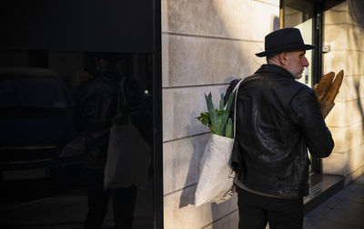 Adult man in hat holding bread and vegetable bag on street. madrid, spain