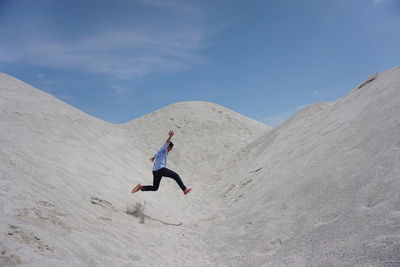 Man on sand dune in desert against clear sky