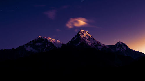 Scenic view of snowcapped mountains against sky at night