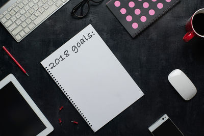 High angle view of diary with technologies on table