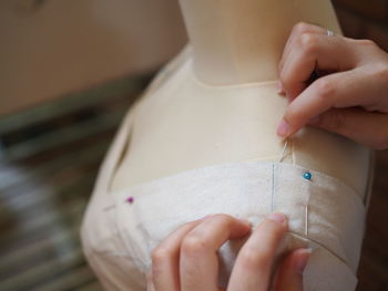 Close-up of woman hands pushing straight pins in mannequin