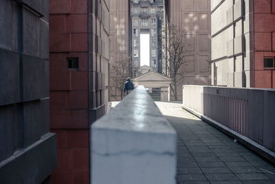 Rear view of man walking on footpath amidst buildings