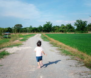 Rear view of lovely adorable charming little girl running on rural road.