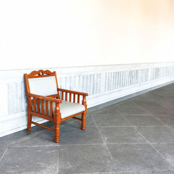 Empty chair on tiled floor against clear sky