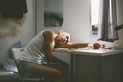 Side view of man sitting on table at home