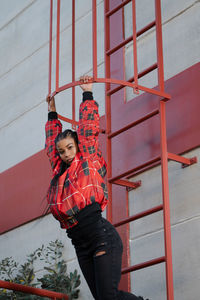 Smiling girl with african braids on a red metal ladder