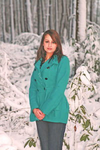 Portrait of young woman standing on snow covered land