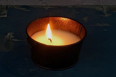 Close-up of illuminated tea light candle against wall