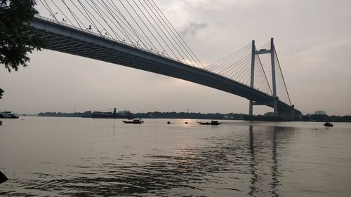 Suspension bridge over river against sky
