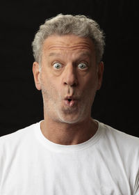 Close-up portrait of a serious man against black background