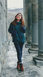 Portrait of young woman standing against built structure