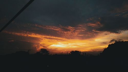 Silhouette landscape against dramatic sky during sunset