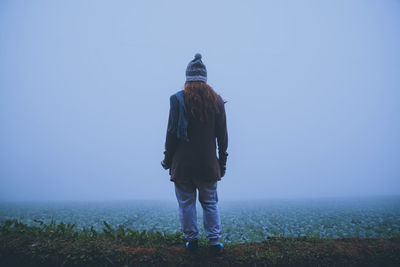 Rear view of woman standing at farm at morning