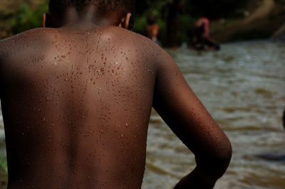 Rear view of shirtless man standing in water