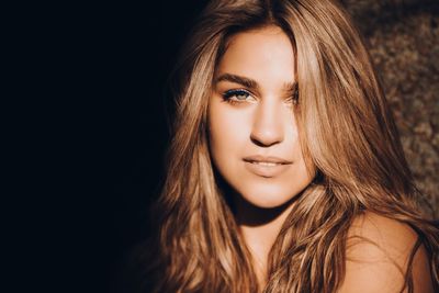 Close-up portrait of a beautiful young woman over black background