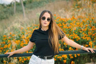 Young woman wearing sunglasses standing against plants