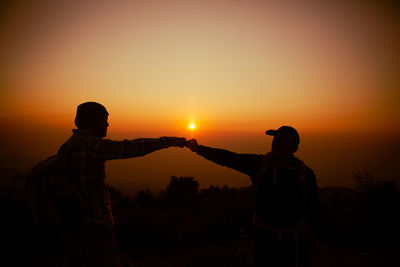 Hiker with backpack relaxing on top of a mountain and enjoying valley view during sunrise