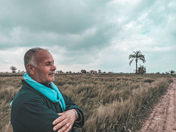 Man with umbrella on field against sky