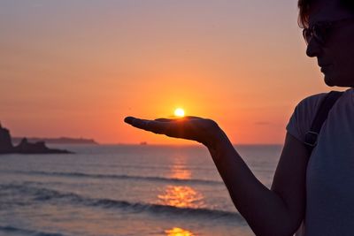 Optical illusion of woman holding sun at beach