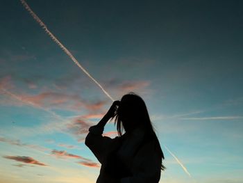 Silhouette of woman against blue sky and pink clouds