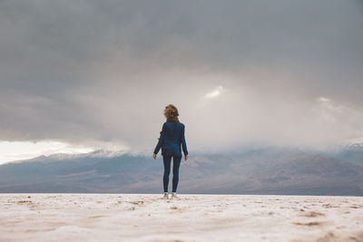 Rear view of woman standing on snow covered land against sky