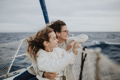 Mother and daughter looking at view while traveling on sailboat during vacation