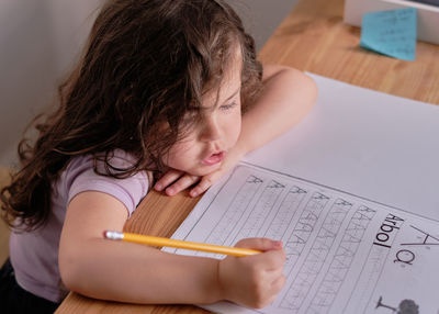 Young pretty is girl tracing letters in a book