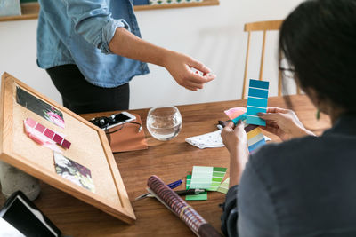 Midsection of woman holding paper while sitting on table