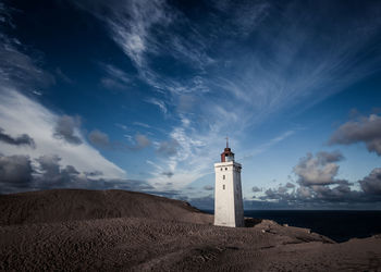 Lighthouse on beach against sky