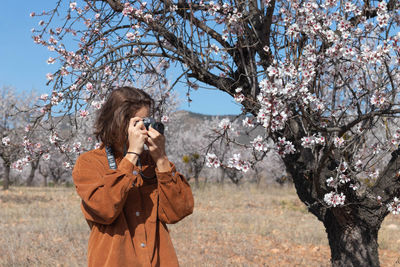 Side view of woman photographing tree
