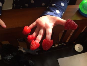 Close-up of hand holding strawberries on table