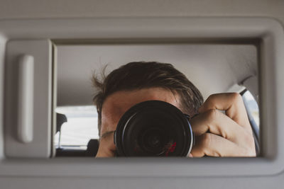 Portrait of man photographing camera at home