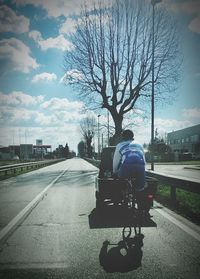 Rear view of man riding motorcycle on road against sky