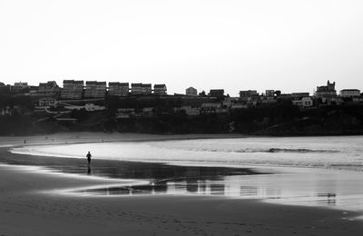 Buildings by sea against clear sky
