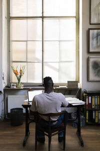 Rear view of woman sitting on chair at home