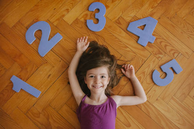 Portrait of a smiling girl lying on hardwood floor