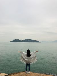 Rear view of woman standing on sea against sky