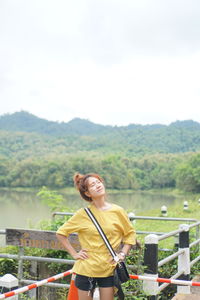 Smiling young woman standing on landscape against sky