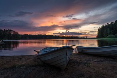 Boat moored on lake against sky during sunset