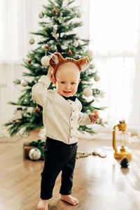 Funny boy in a sweater and tiger ears on the background of a christmas tree. the symbol of the year