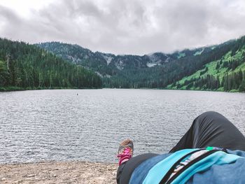 Low section of person in lake against mountains