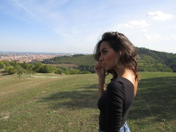 Side view of young woman standing on landscape