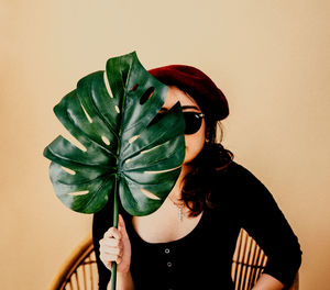 Portrait of woman holding leaf against white background