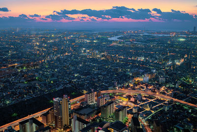 High angle view of illuminated city buildings against sky during sunset