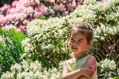 Cute girl standing against flowering plants