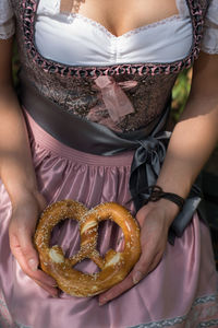 Midsection of woman holding pretzel