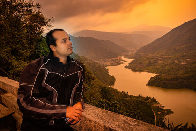 Young man looking away against mountains against sky