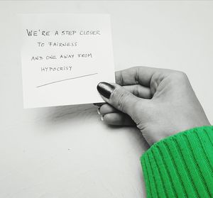 Midsection of person holding paper with text on table