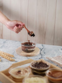 Midsection of person spooning a cup of oreo dessert on table