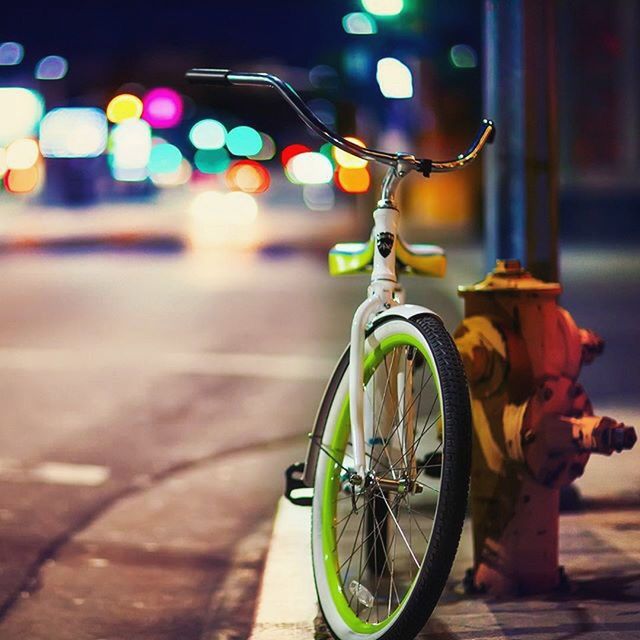 bicycle, transportation, mode of transport, land vehicle, street, stationary, illuminated, night, parking, parked, multi colored, road, outdoors, blurred motion, focus on foreground, city, travel, circle, incidental people, wheel